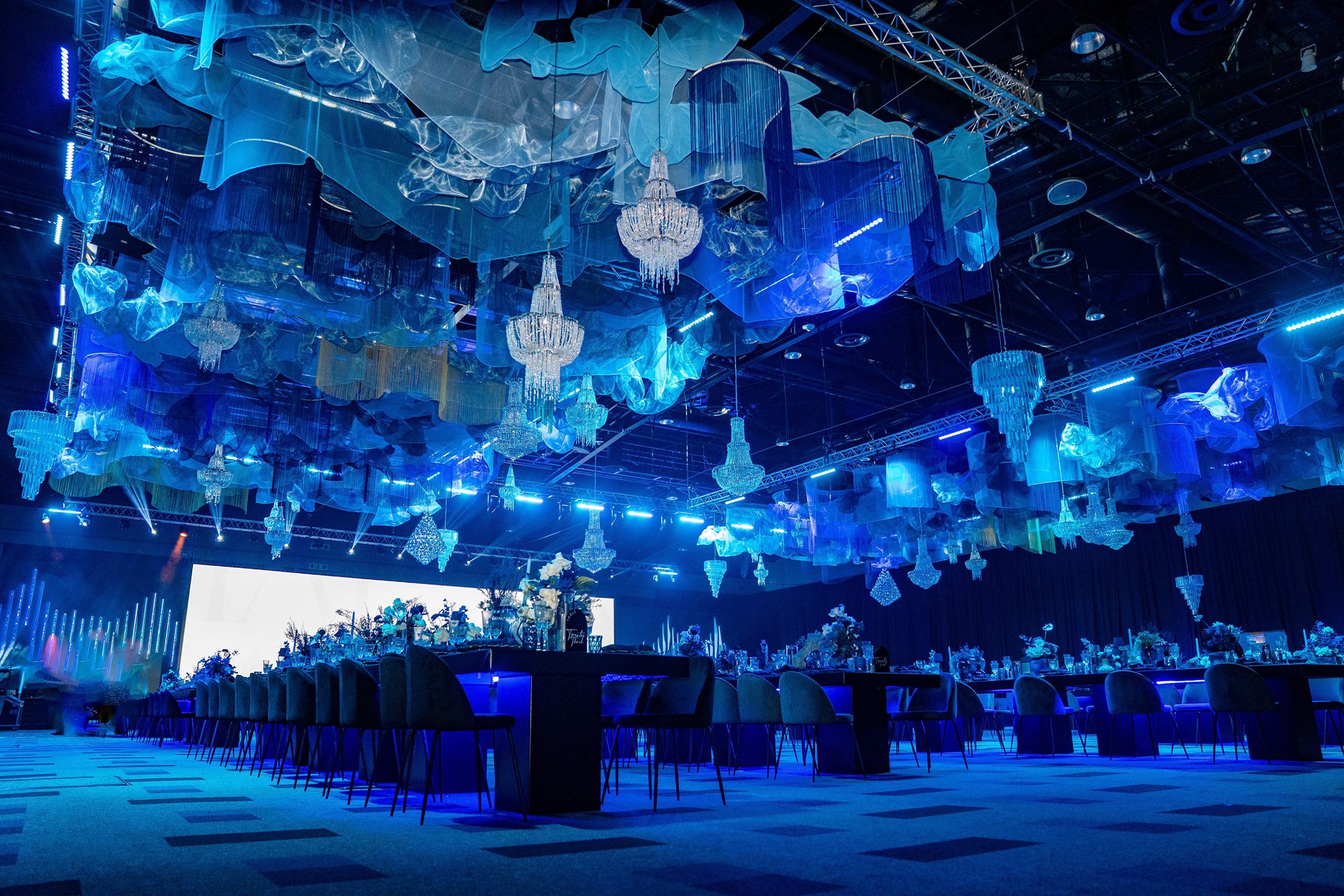 A gala dinner hall lit in blue, set for a corporate awards evening