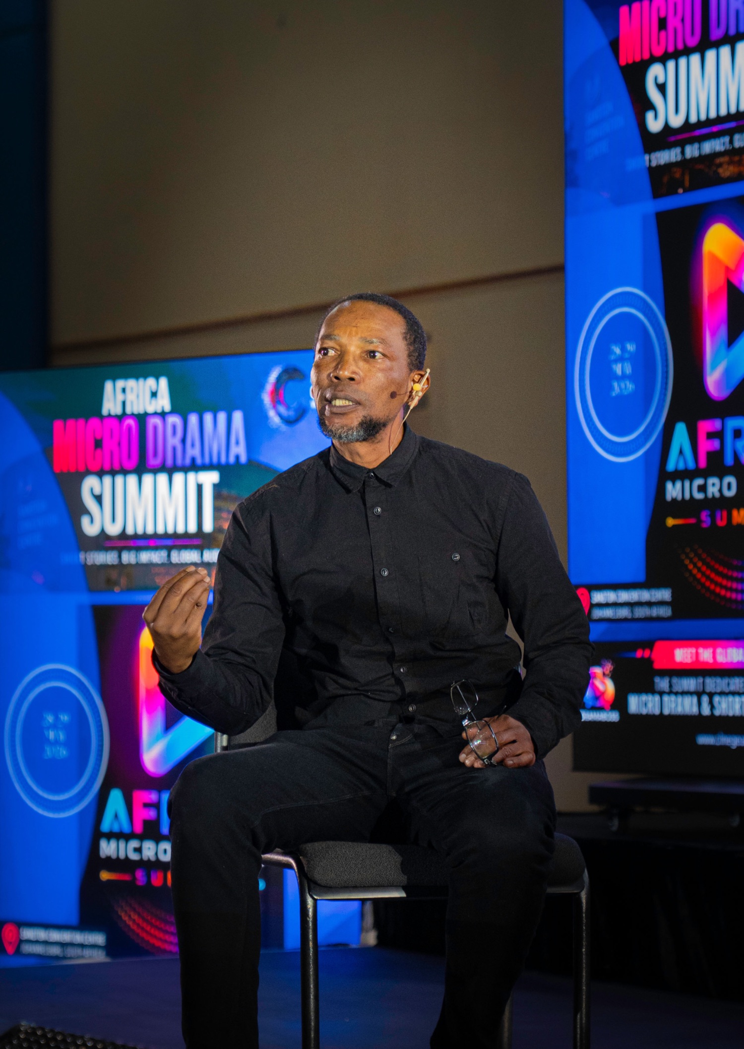 Speaker seated on stage at a summit