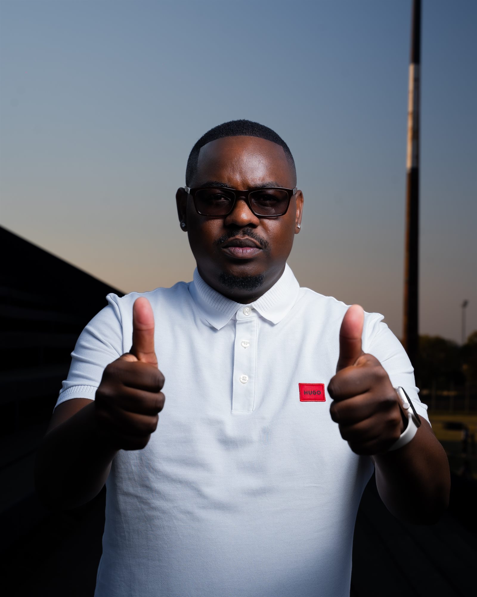 Portrait of a man giving a double thumbs up against an evening sky