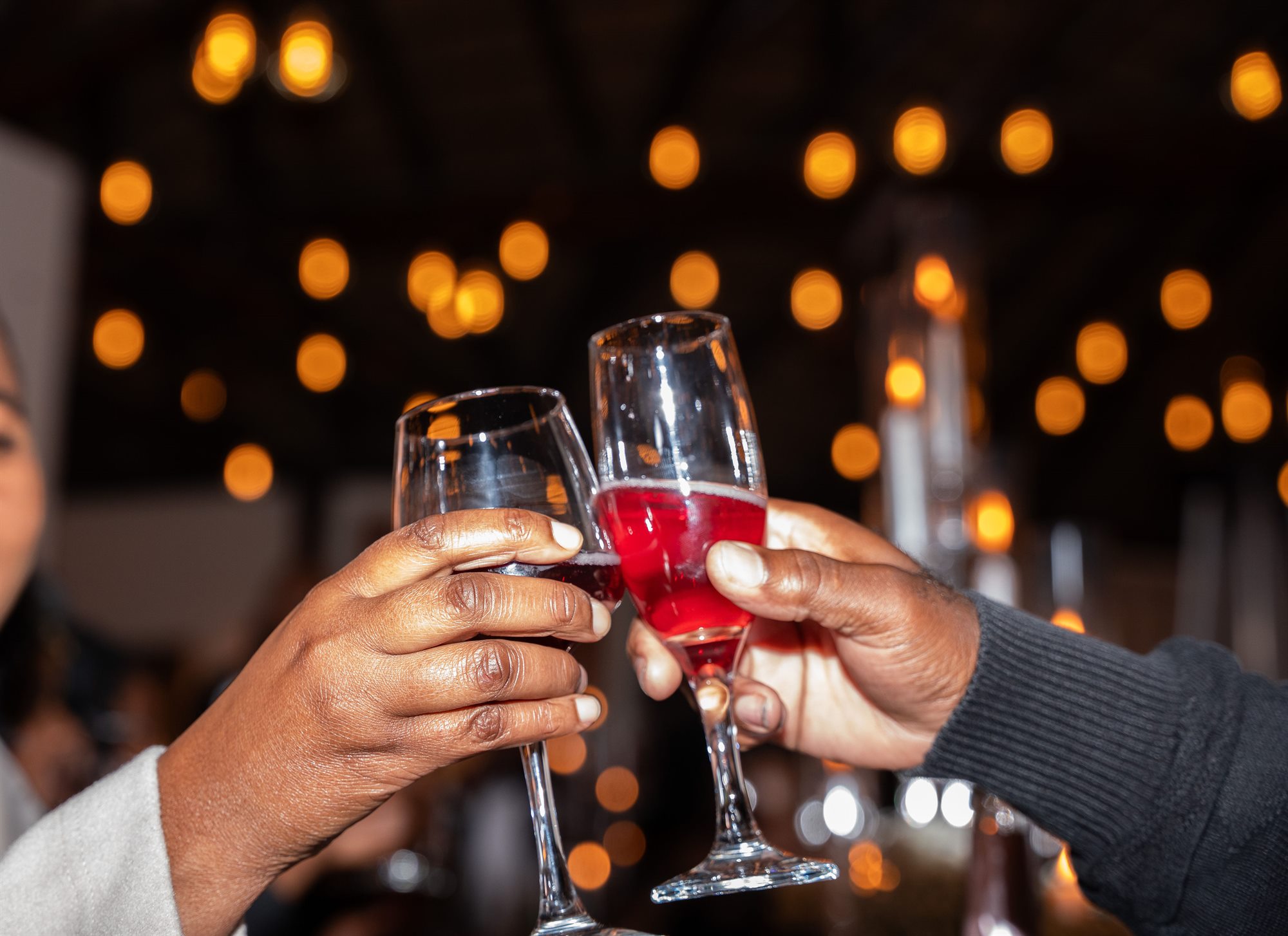 Guests clinking champagne glasses under warm bokeh lights