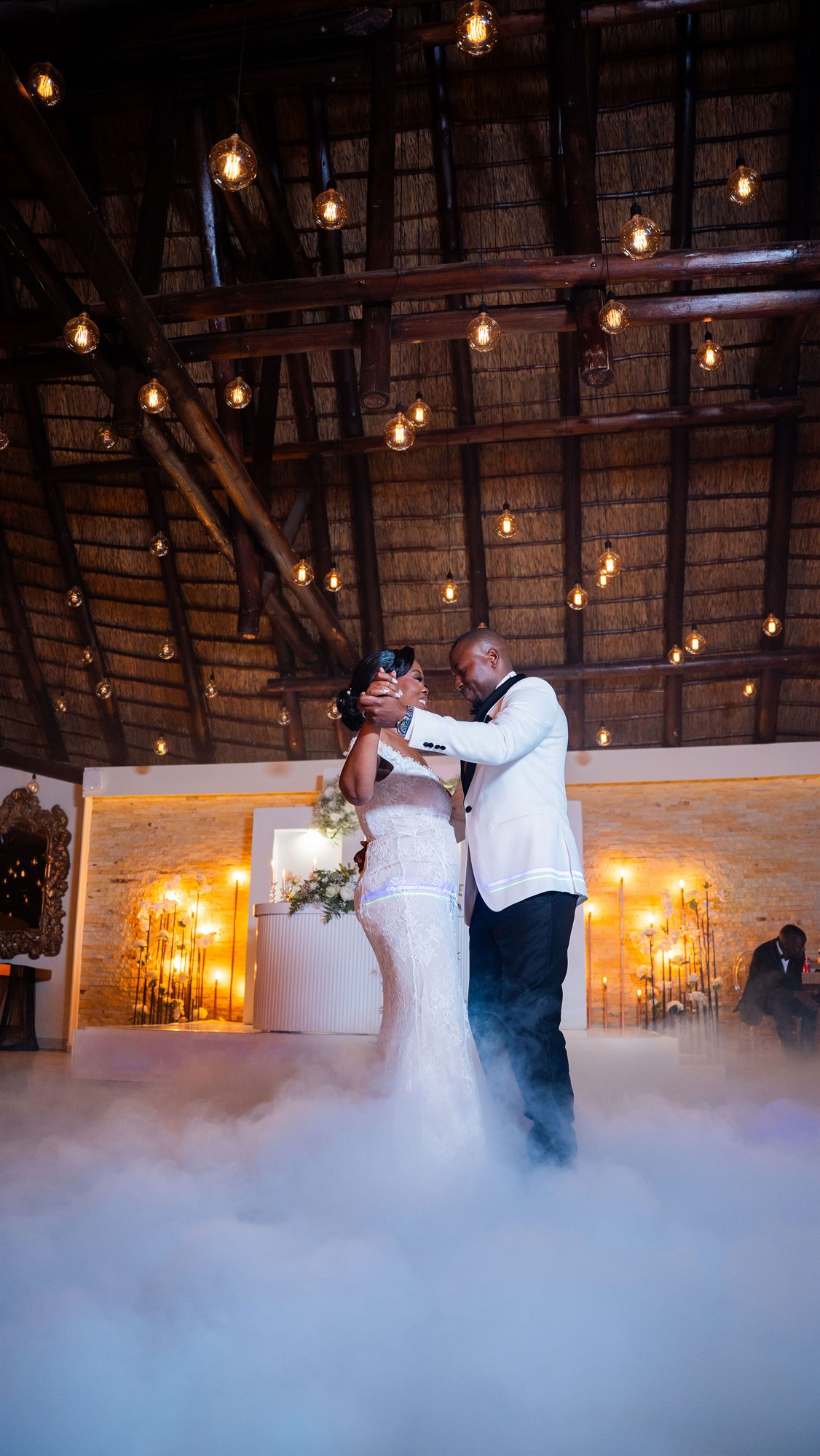 Newlyweds during their first dance under warm festoon lighting